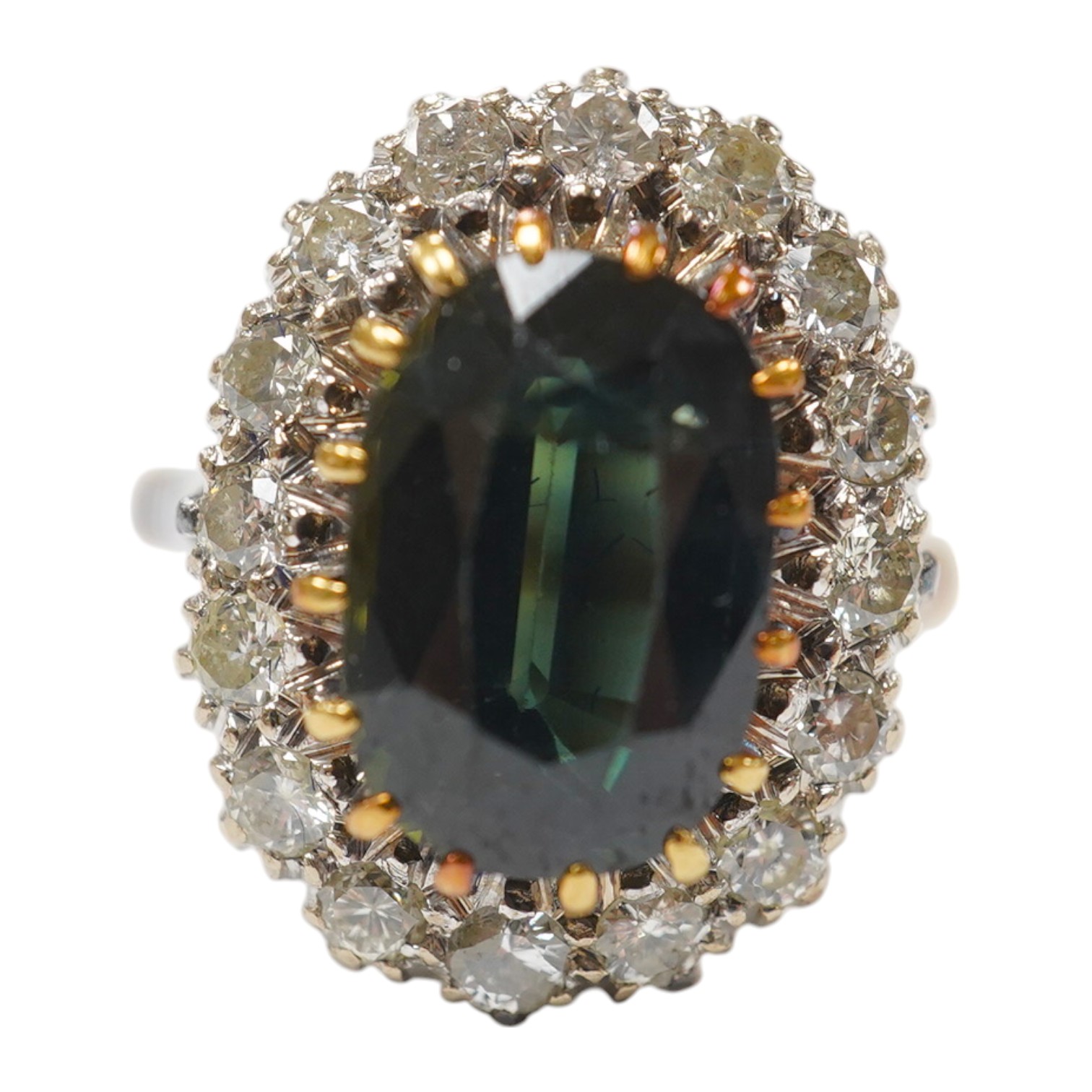 An 18ct, dark green sapphire and diamond set oval cluster ring, size N/O, gross weight 8.6 grams, the Australian sapphire weighing approximately 3.50ct, the total diamond weight approximately 0.64ct. Condition - fair